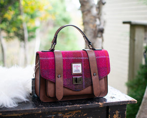 Pink and brown handbag on a wooden surface with a blurred natural background