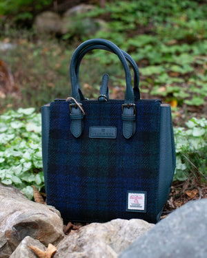Blue plaid handbag on a natural background with greenery and rocks.